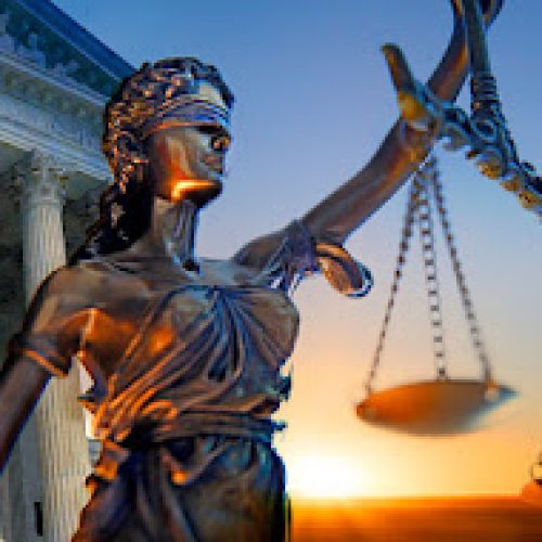 A statue of the blindfolded lady justice in front of the United States Supreme Court building as the sun rises in the distance symbolizing the dawning of a new era.